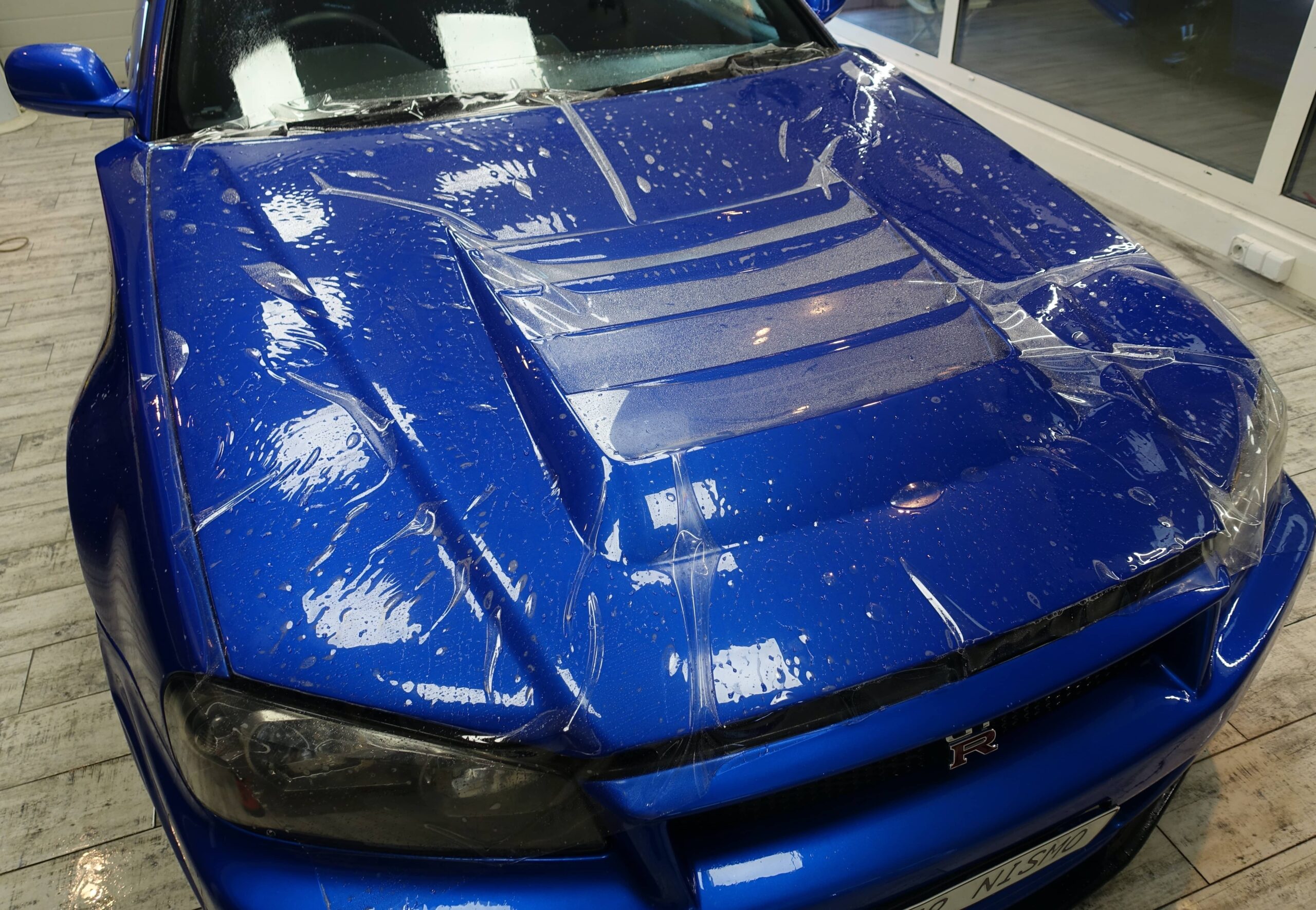 niebieska maska samochodu w trakcie nakładania folii ochronnej ppf