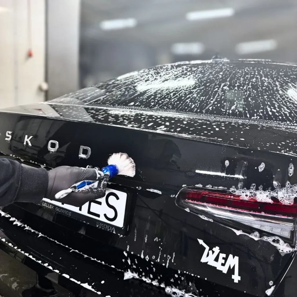 Detailer myjący czarny samochód metodą bezpiecznego mycia detailingowego bez ryzyka zarysowań lakieru.